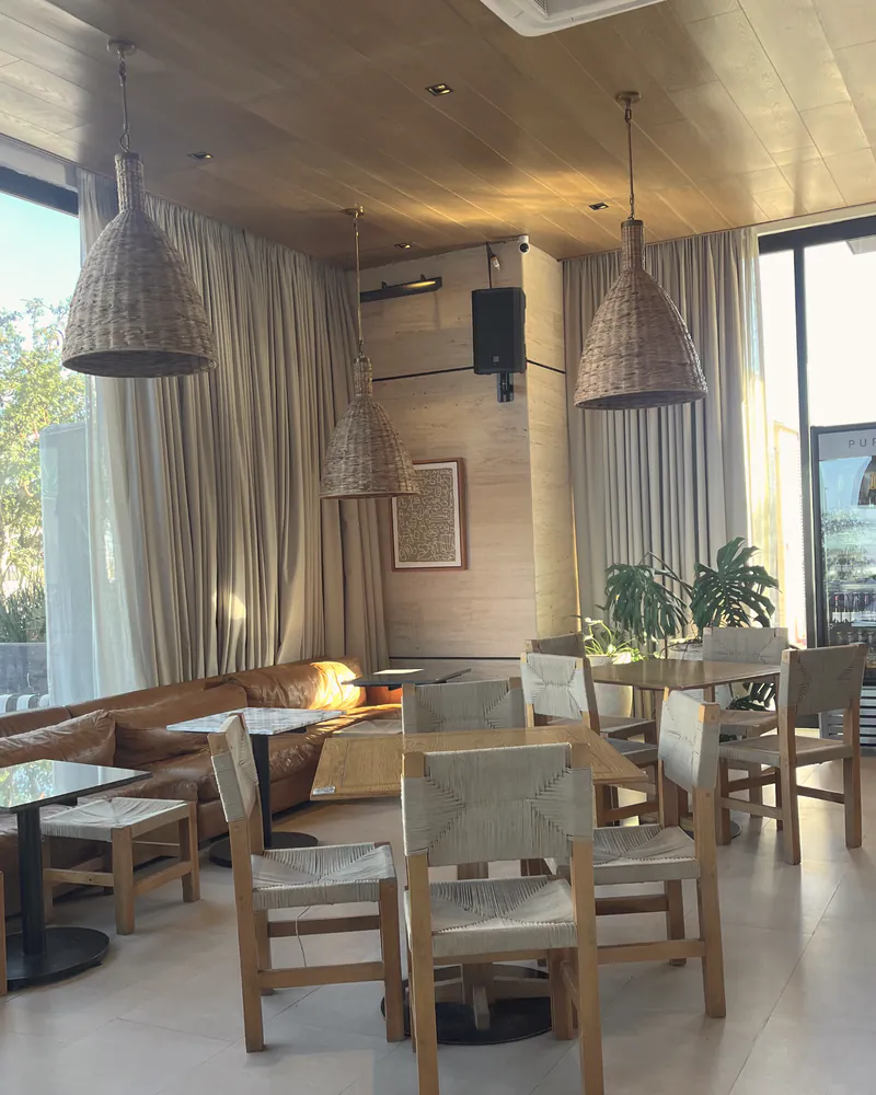 A bright café interior with rattan pendant lights and wood tables