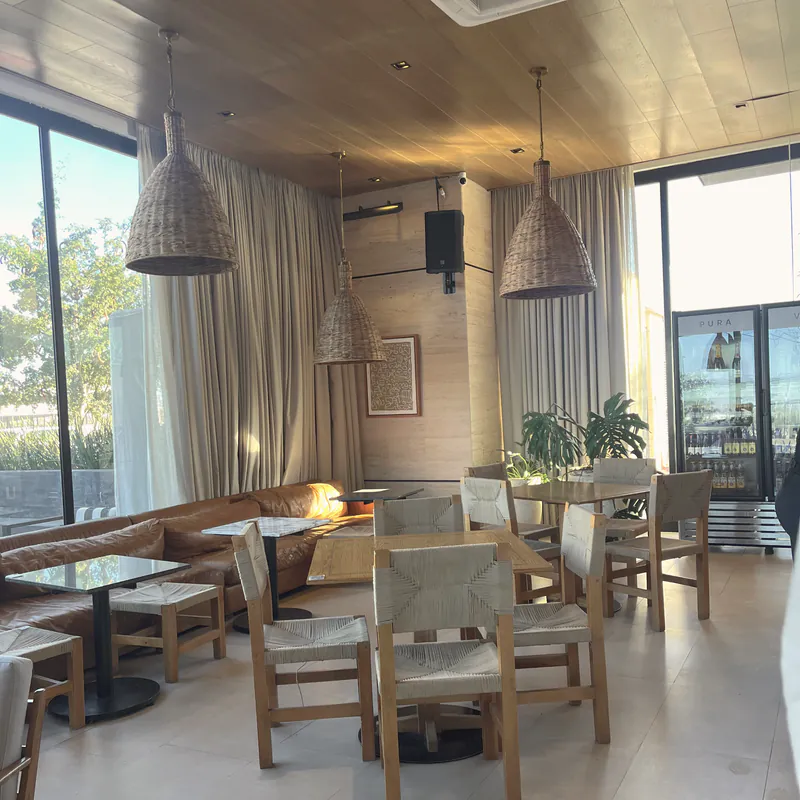 A bright café interior with rattan pendant lights and wood tables