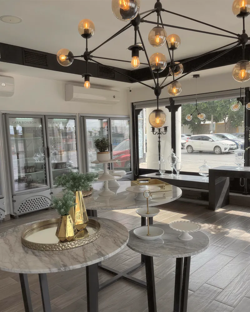 A styled studio with a black chandelier and marble bistro tables