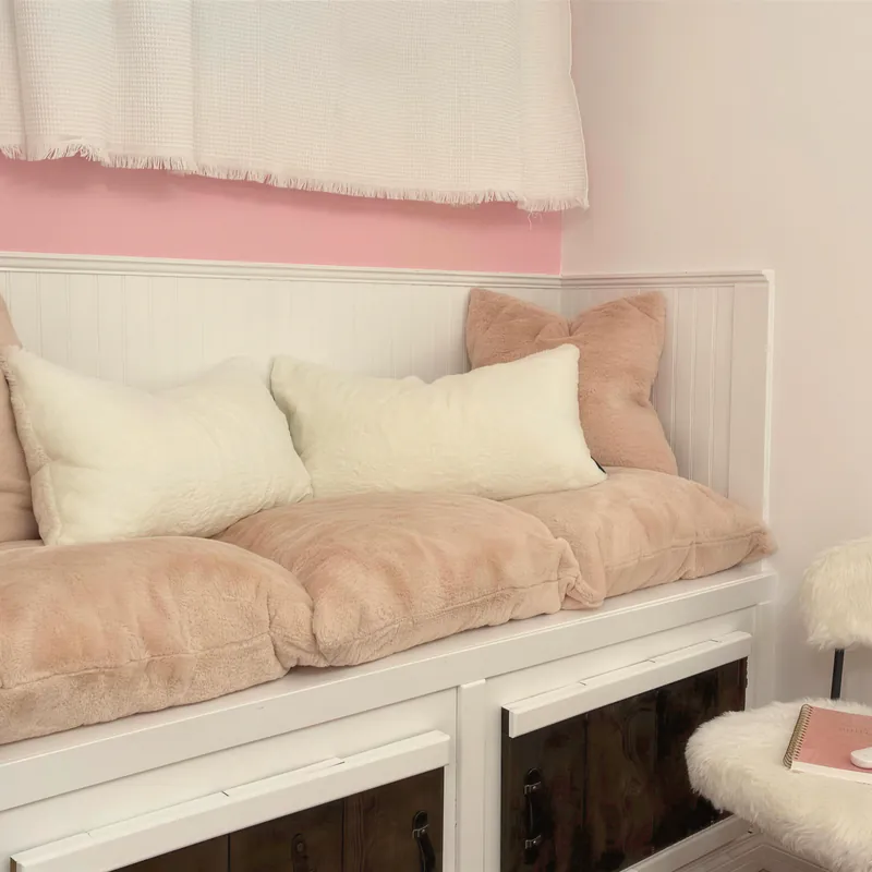 A blush-pink daybed with soft cushions in a renovated studio