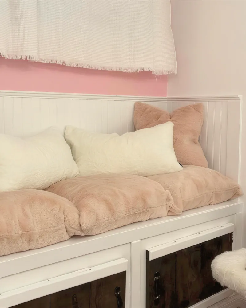 A blush-pink daybed with soft cushions in a renovated studio
