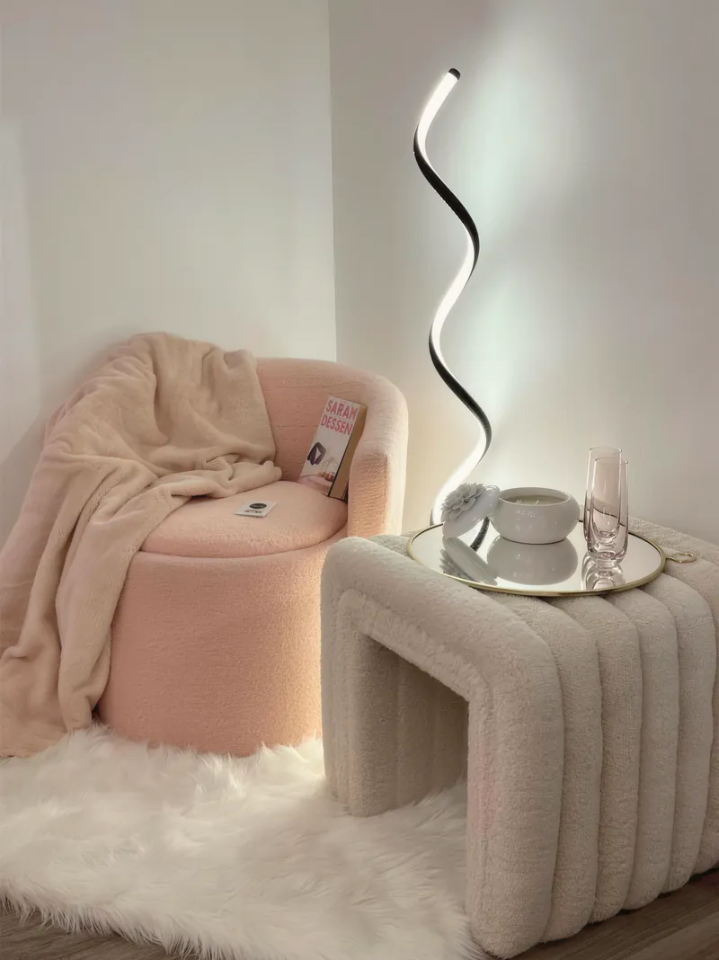 A pink velvet chair with a sculptural lamp and a faux-fur rug
