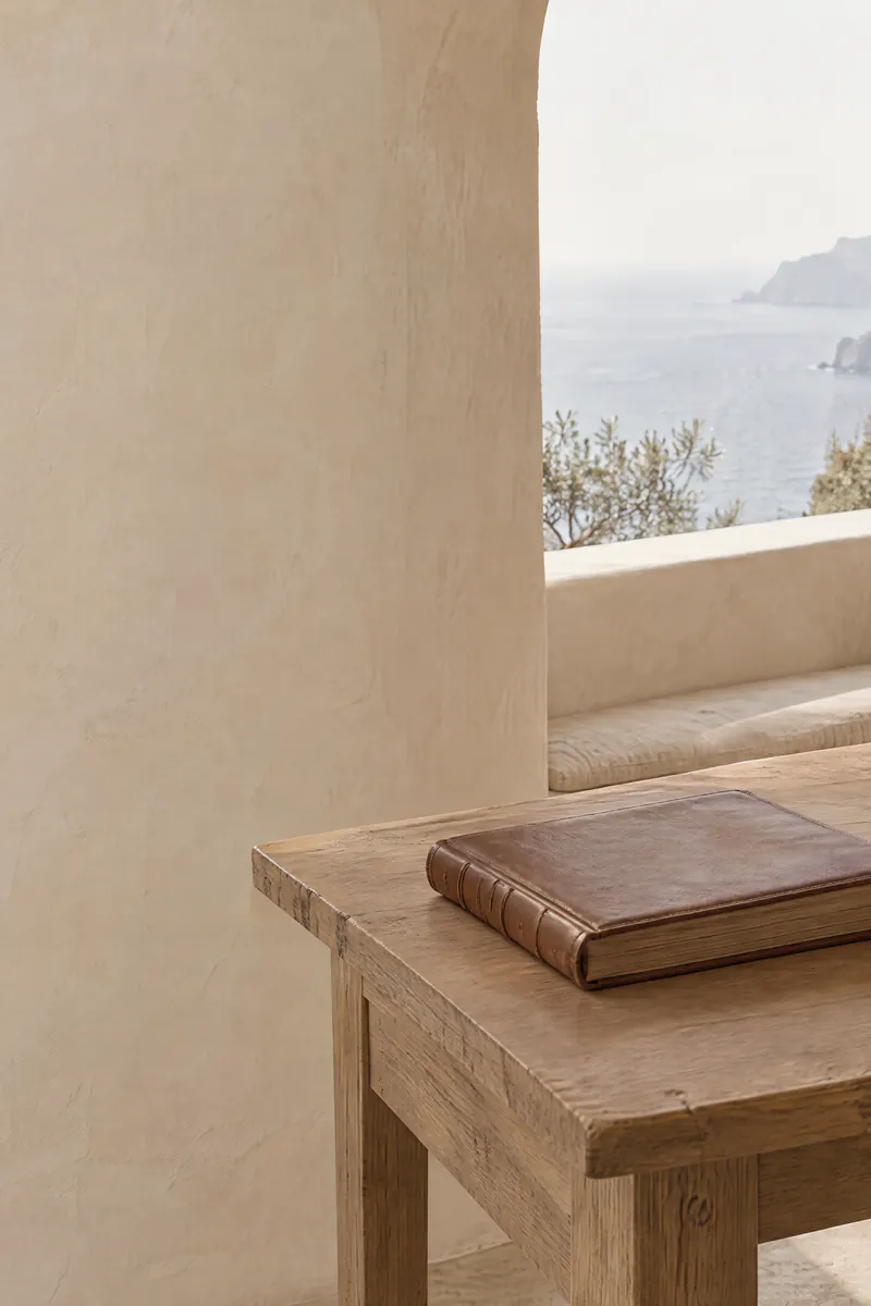 A calm writing desk with a leather ledger under an arched window