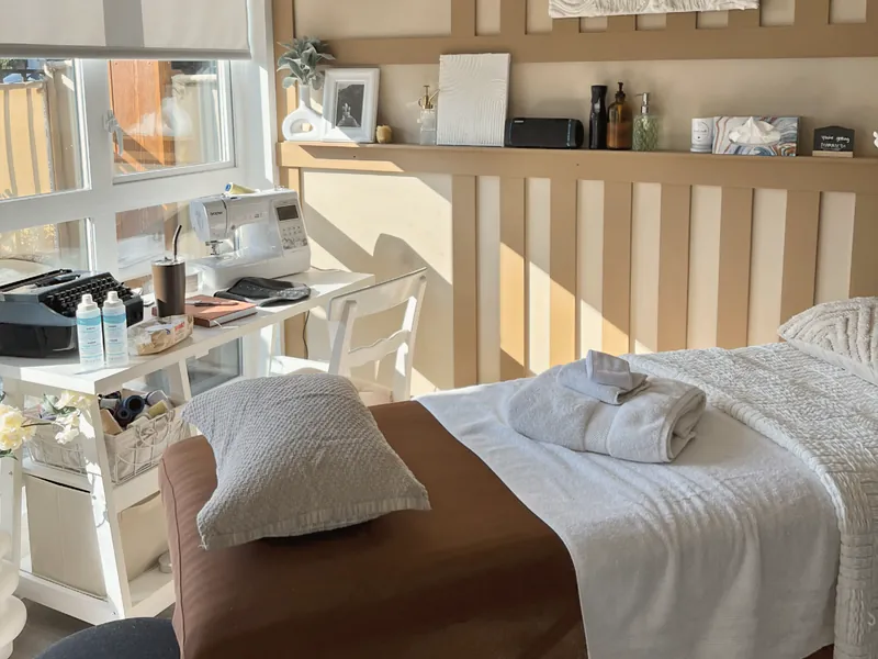 A calm, finished treatment studio with a massage table and warm neutral décor