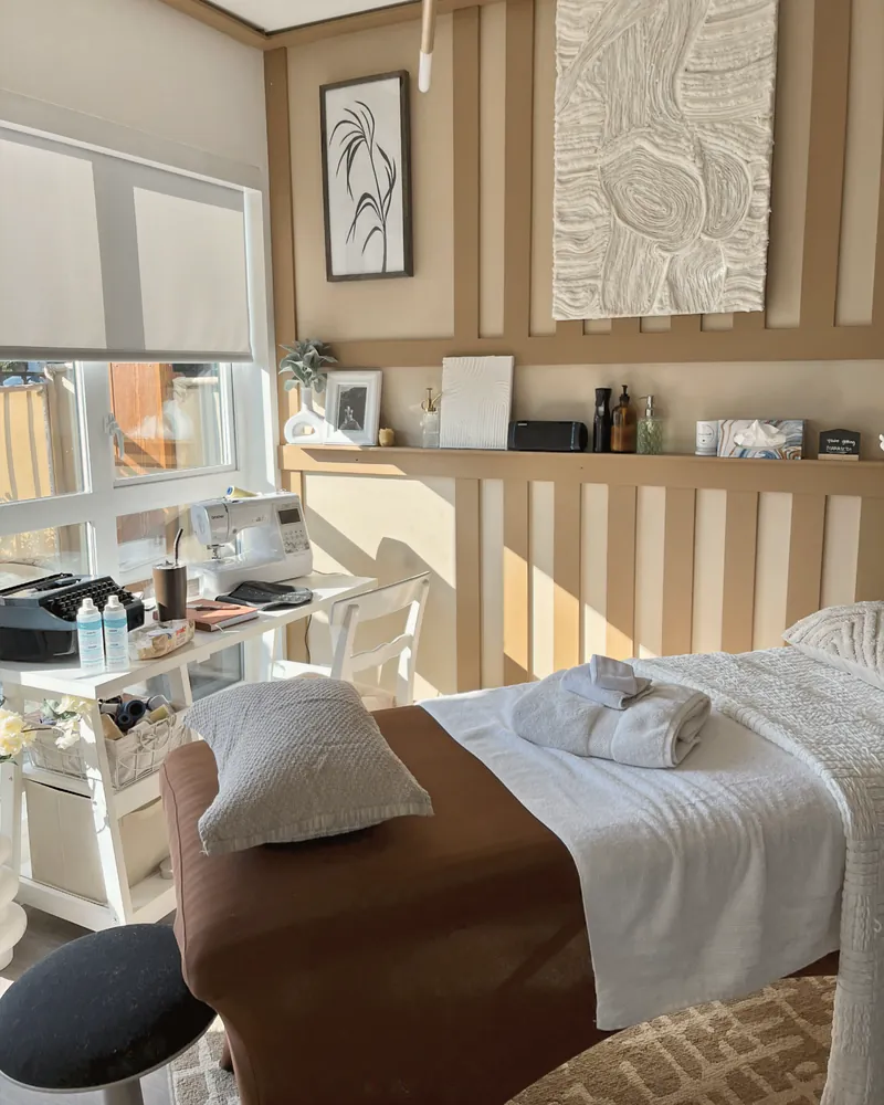 A calm, finished treatment studio with a massage table and warm neutral décor